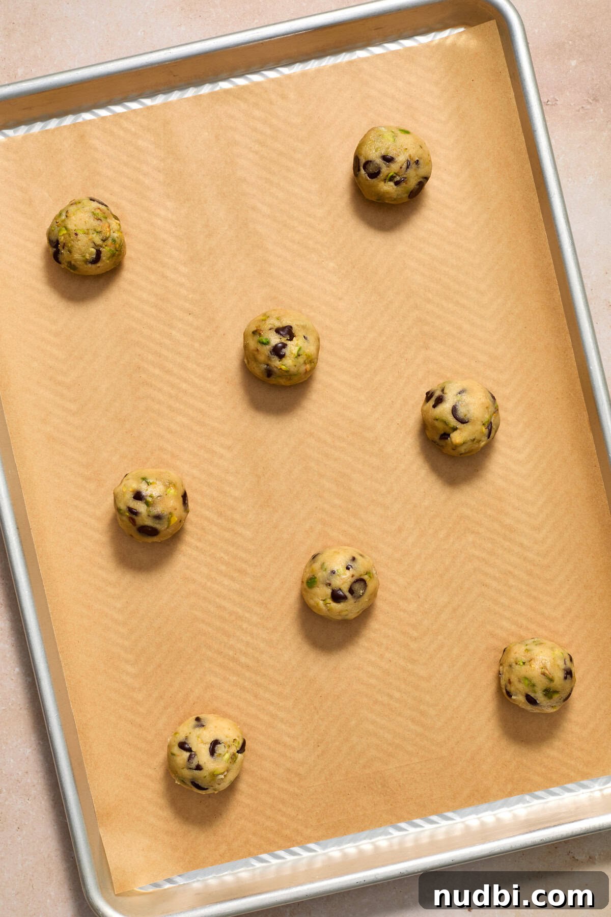 Chewy Pistachio Chocolate Chip Cookies Recipe for Home Bakers 13 Cookie dough balls on parchment lined baking sheet.