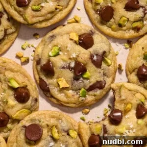Chewy Pistachio Chocolate Chip Cookies Recipe for Home Bakers 17 Pistachio chocolate chip cookies arranged on surface.