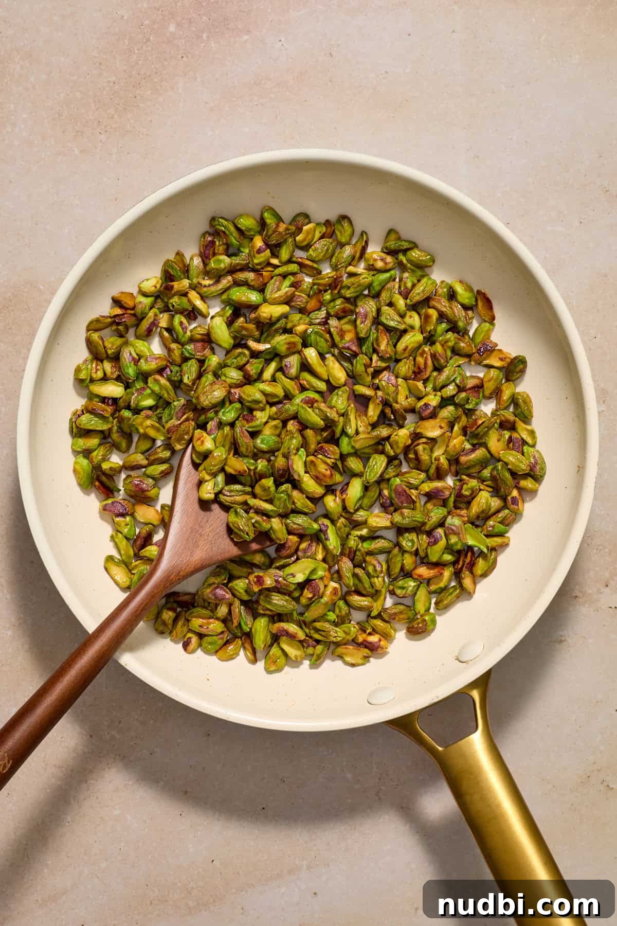 Chewy Pistachio Chocolate Chip Cookies Recipe for Home Bakers 5 Pistachios in skillet with wooden spoon.