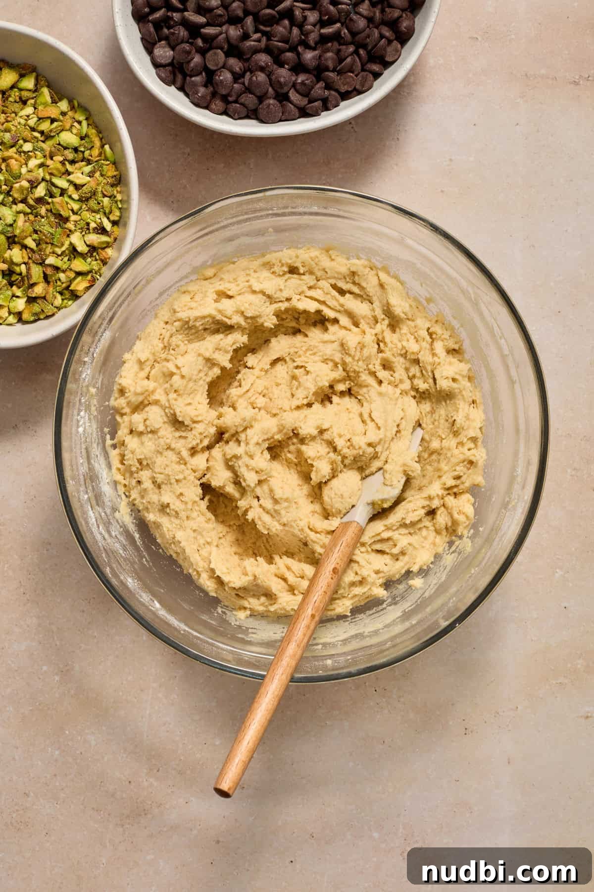 Chewy Pistachio Chocolate Chip Cookies Recipe for Home Bakers 10 Cookie dough in bowl with pistachios and chocolate chips beside.
