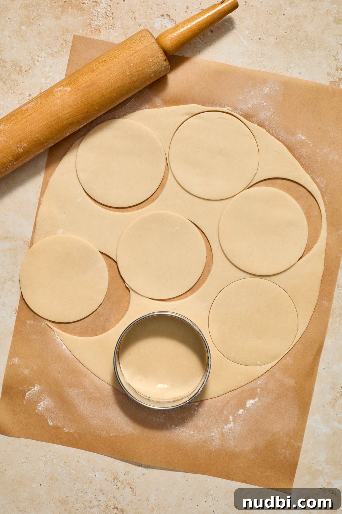 Mini Pumpkin Pies Recipe: Perfect Individual Pumpkin Tarts 7 Pie crust rolled on parchment paper with rolling pin and biscuit cutter.