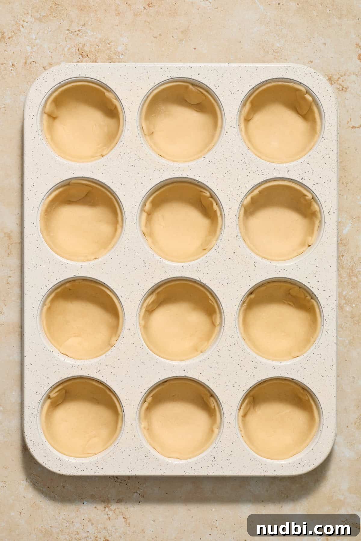 Mini Pumpkin Pies Recipe: Perfect Individual Pumpkin Tarts 8 Muffin tin with pie crust in each muffin cavity.