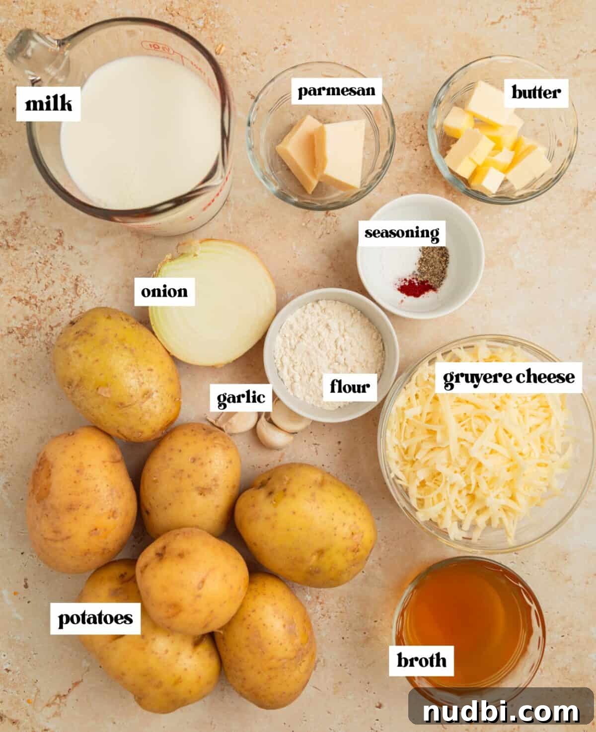 Creamy Gruyère Scalloped Potatoes with Garlic and Thyme 4 Labeled ingredients on surface including cheese, potatoes, and more.