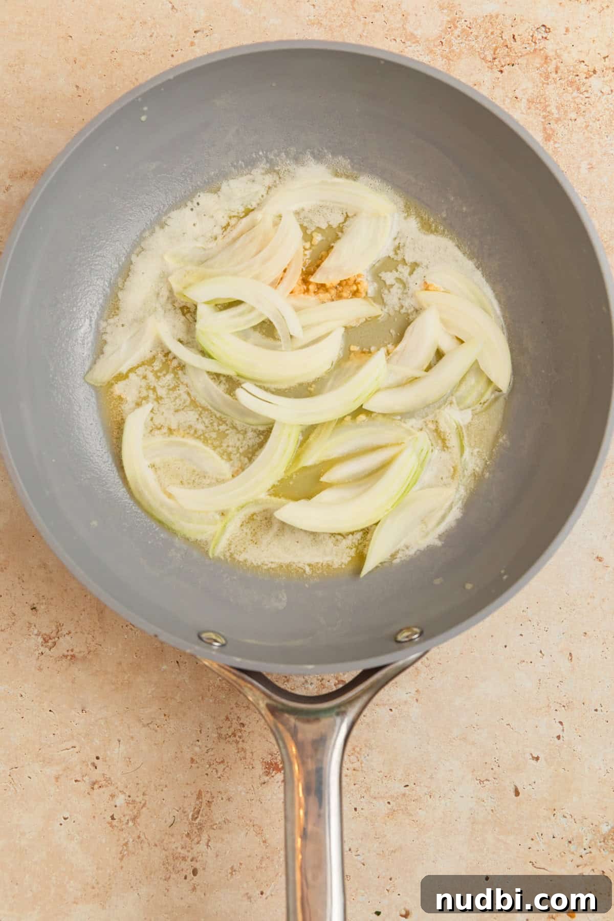 Creamy Gruyère Scalloped Potatoes with Garlic and Thyme 6 Onions and butter with garlic in skillet.