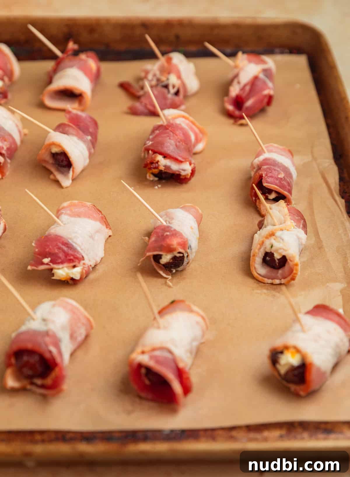Bacon-Wrapped Dates Stuffed with Goat Cheese and Almonds 9 Bacon wrapped dates on baking sheet.