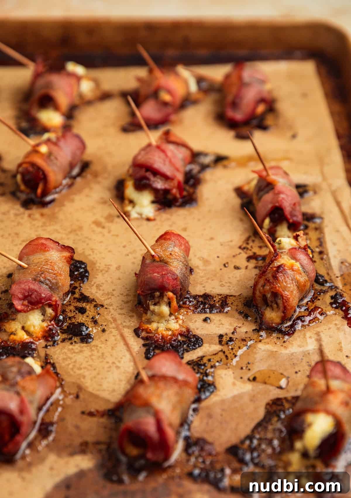 Bacon-Wrapped Dates Stuffed with Goat Cheese and Almonds 10 Cooked bacon wrapped stuffed dates on pan.