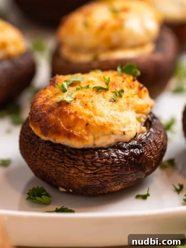 Crispy Goat Cheese Puff Pastry Tart Recipe 12 Air fried stuffed mushrooms on white plate topped with chopped parsley.