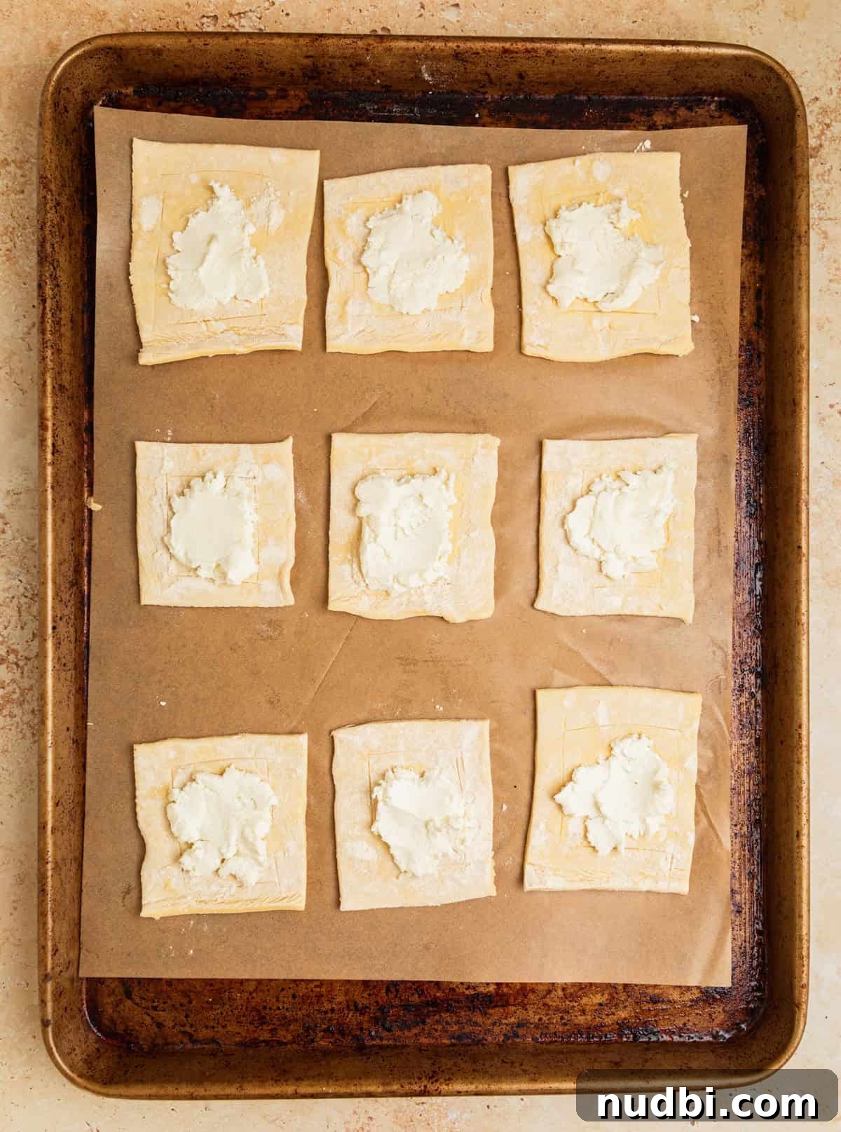 Crispy Goat Cheese Puff Pastry Tart Recipe 6 Goat cheese spread on puff pastry squares on parchment lined sheet pan.