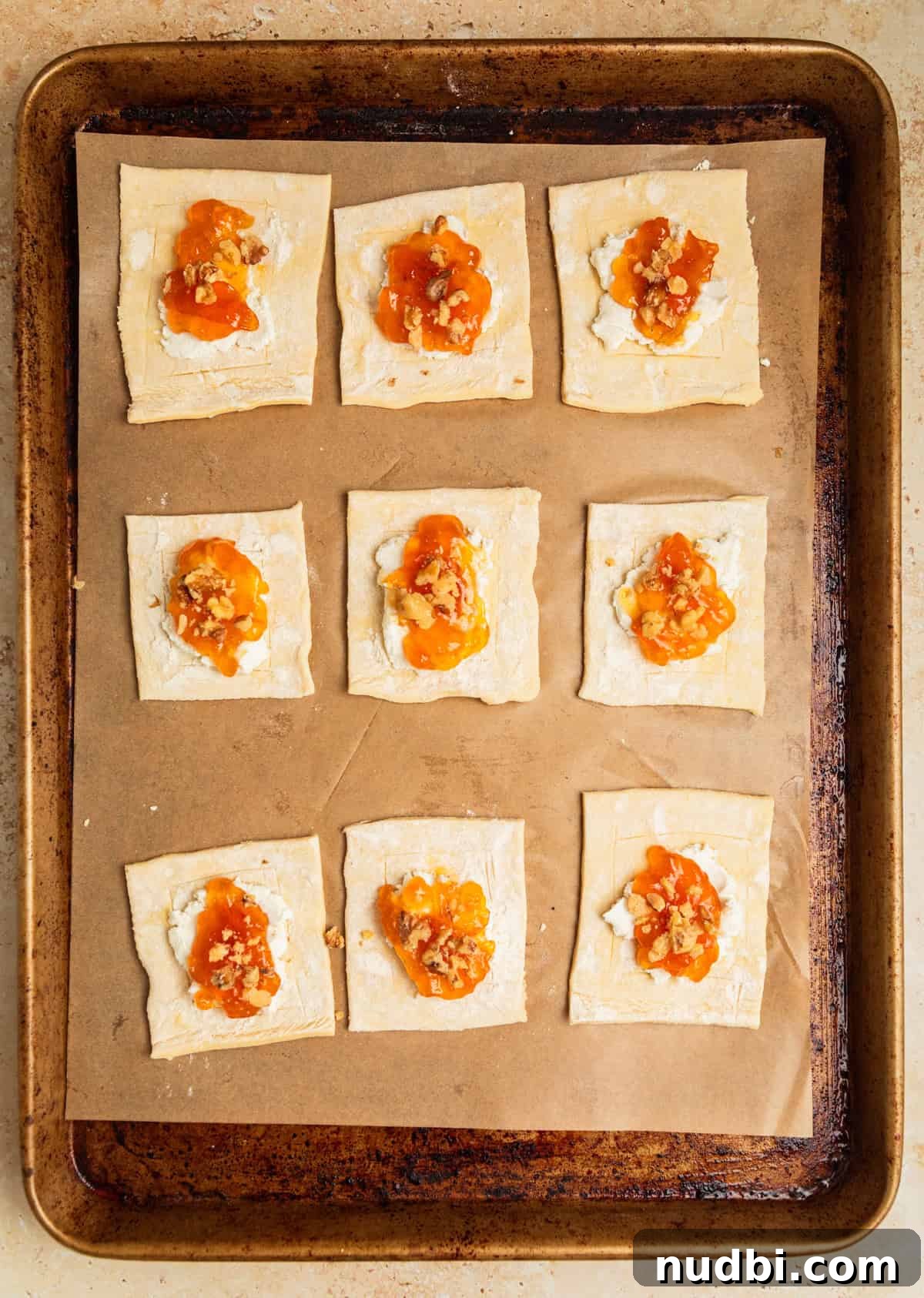 Crispy Goat Cheese Puff Pastry Tart Recipe 7 Puff pastry squares on baking sheet with goat cheese and apricot jam on each.