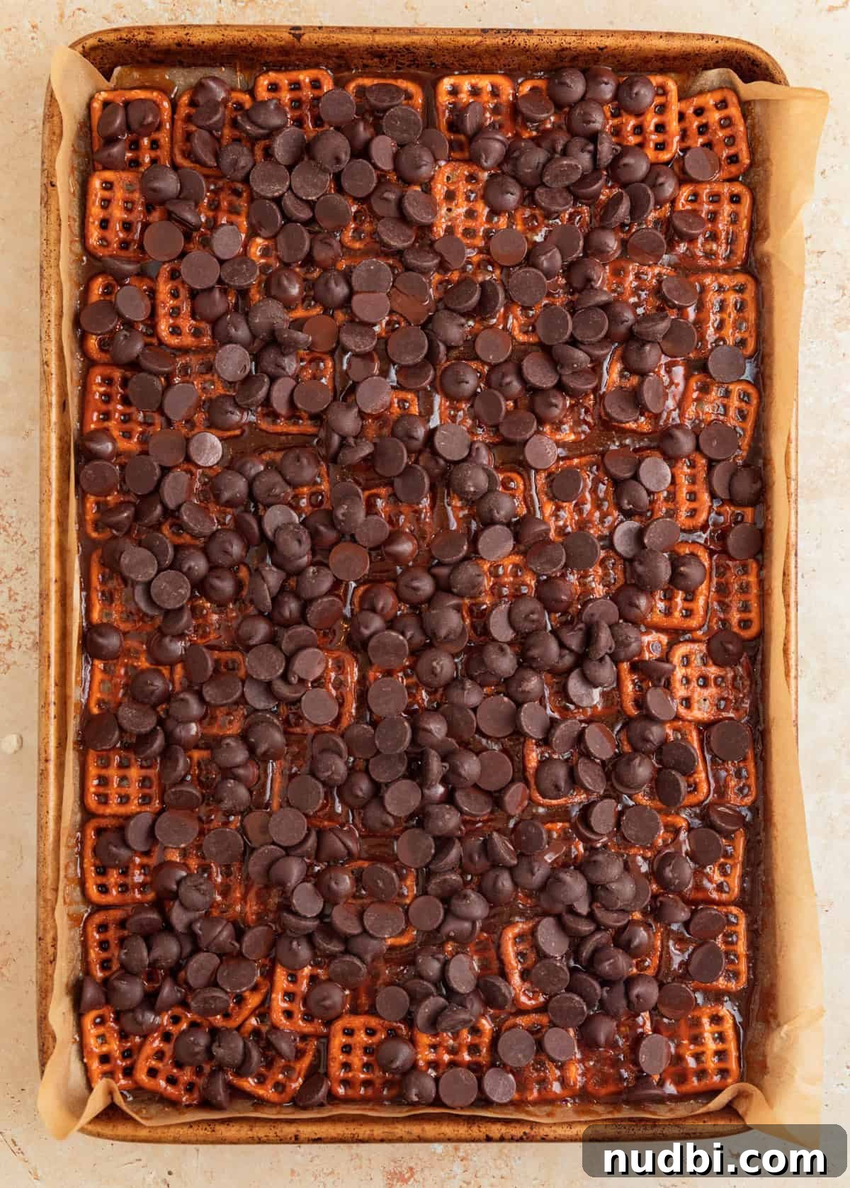 Salted Pretzel Toffee Crunch: Sweet and Salty Candy Recipe 10 Chocolate chips sprinkled over top of pretzel toffee on sheet pan.