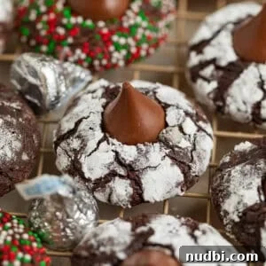 Chocolate Crinkle Blossom Cookies Recipe: Soft Fudgy Chocolate Blossoms 11 Chocolate crinkle cookies with hershey kiss centers on wire rack.