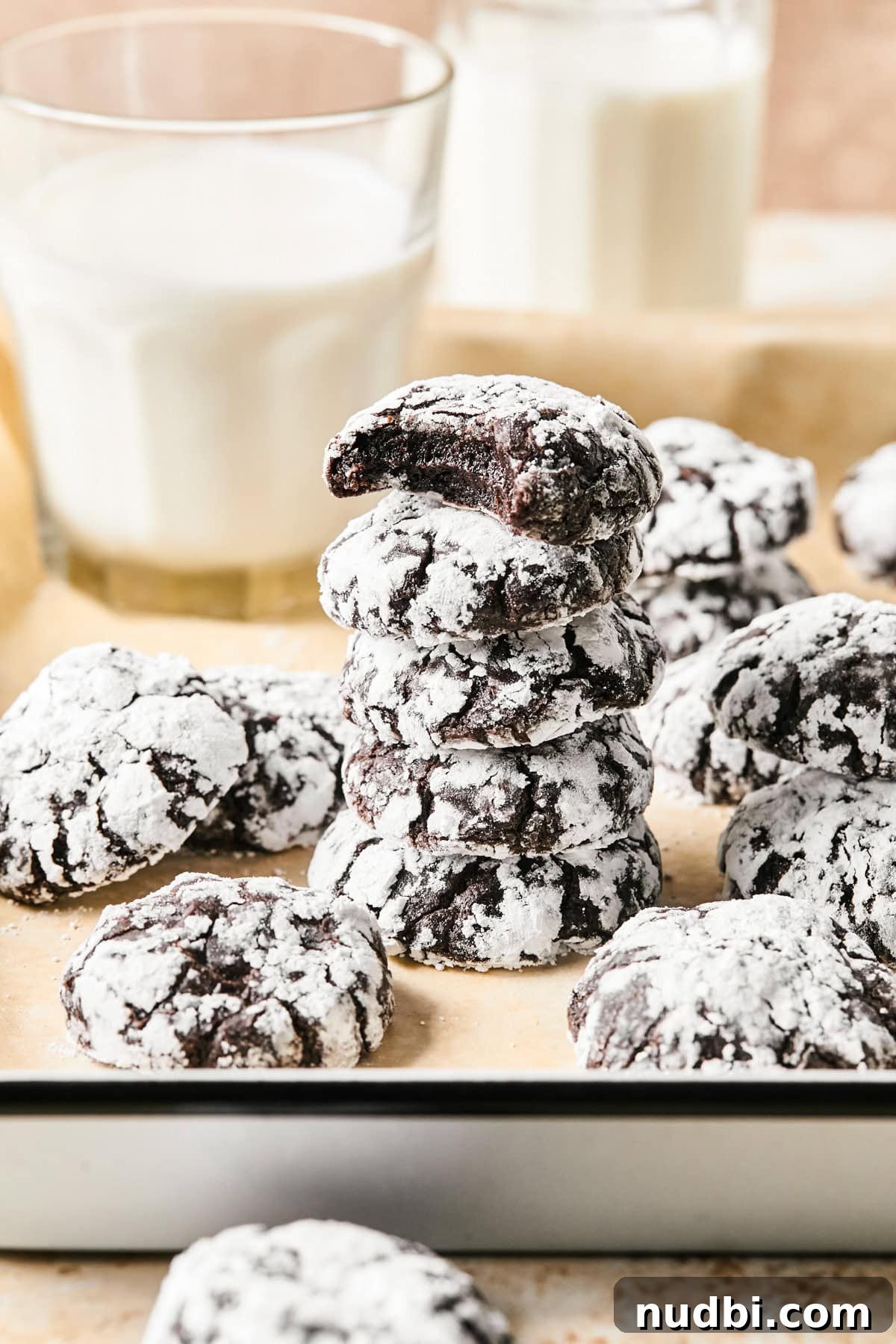 Brownie Crinkle Cookies Recipe — Fudgy, Chewy Chocolate Treats 2 Stack of chocolate crinkle cookies on parchment with milk.