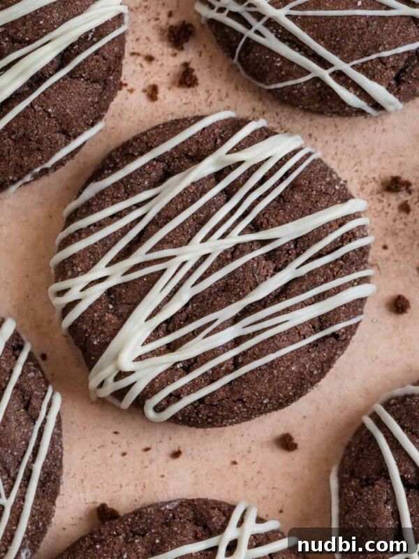 Brownie Crinkle Cookies Recipe — Fudgy, Chewy Chocolate Treats 11 Chocolate cake mix cookies with white chocolate drizzle surrounded by cookie crumbs.