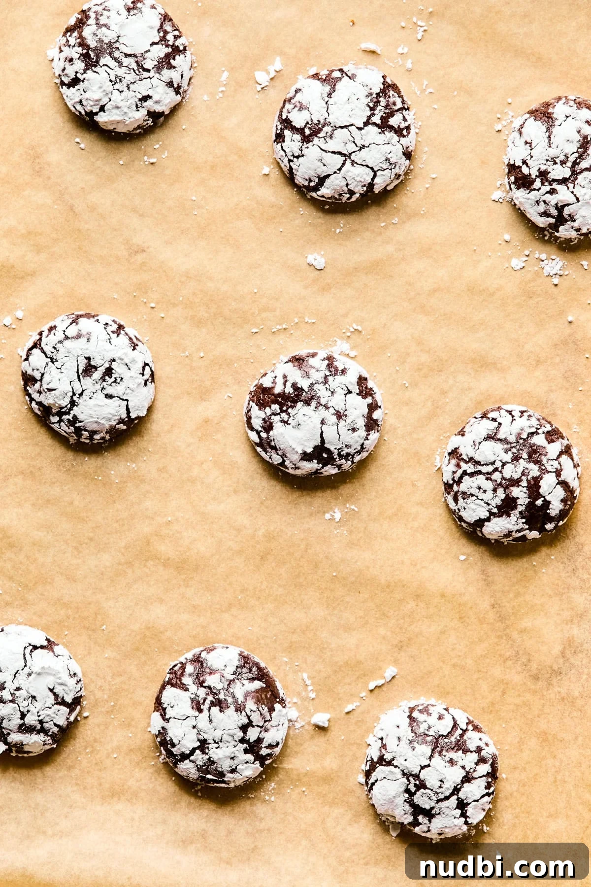 Brownie Crinkle Cookies Recipe — Fudgy, Chewy Chocolate Treats 8 Baked brownie crinkle cookies on parchment.
