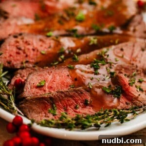 Juicy Top Round Roast Beef Recipe for Tender Slices 10 Sliced roast beef on plate with thyme and pomegranate.