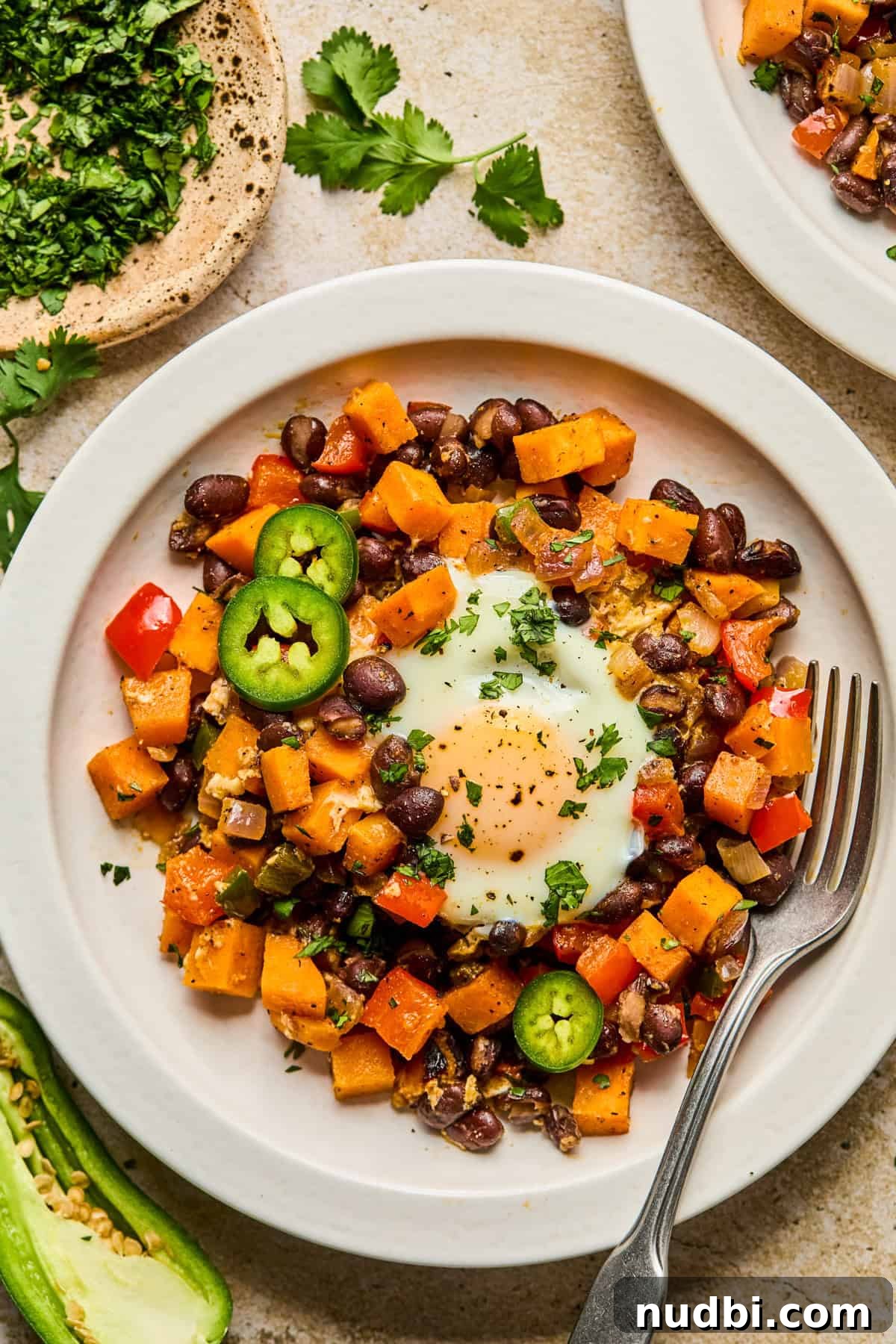 Savory Sweet Potato Breakfast Hash with Crispy Veggies 7 Plate with sweet potato breakfast hash and egg topped with jalapeño and cilantro.