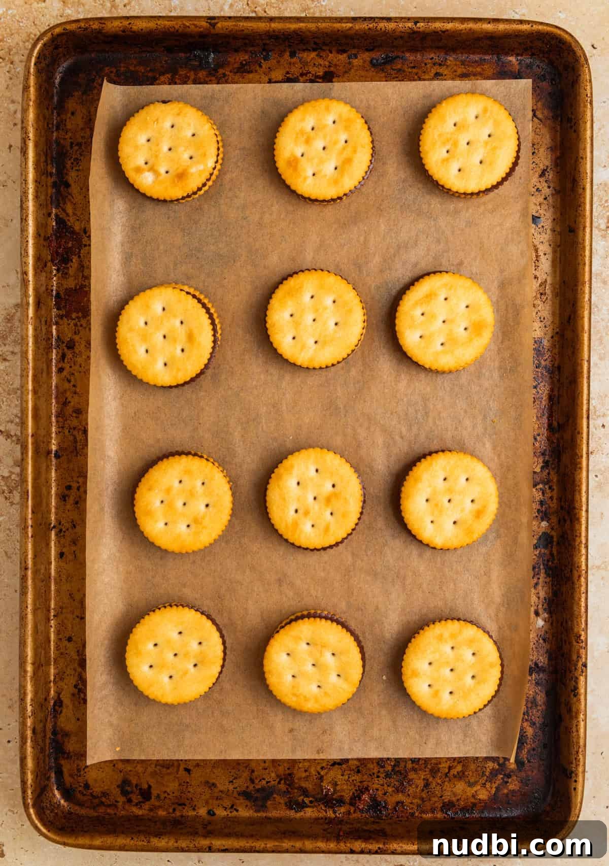 Ritz Cracker Cookies Stuffed with Reese's Cups 7 Crackers topped on melted chocolate peanut butter cut candy on parchment lined cookie sheet.