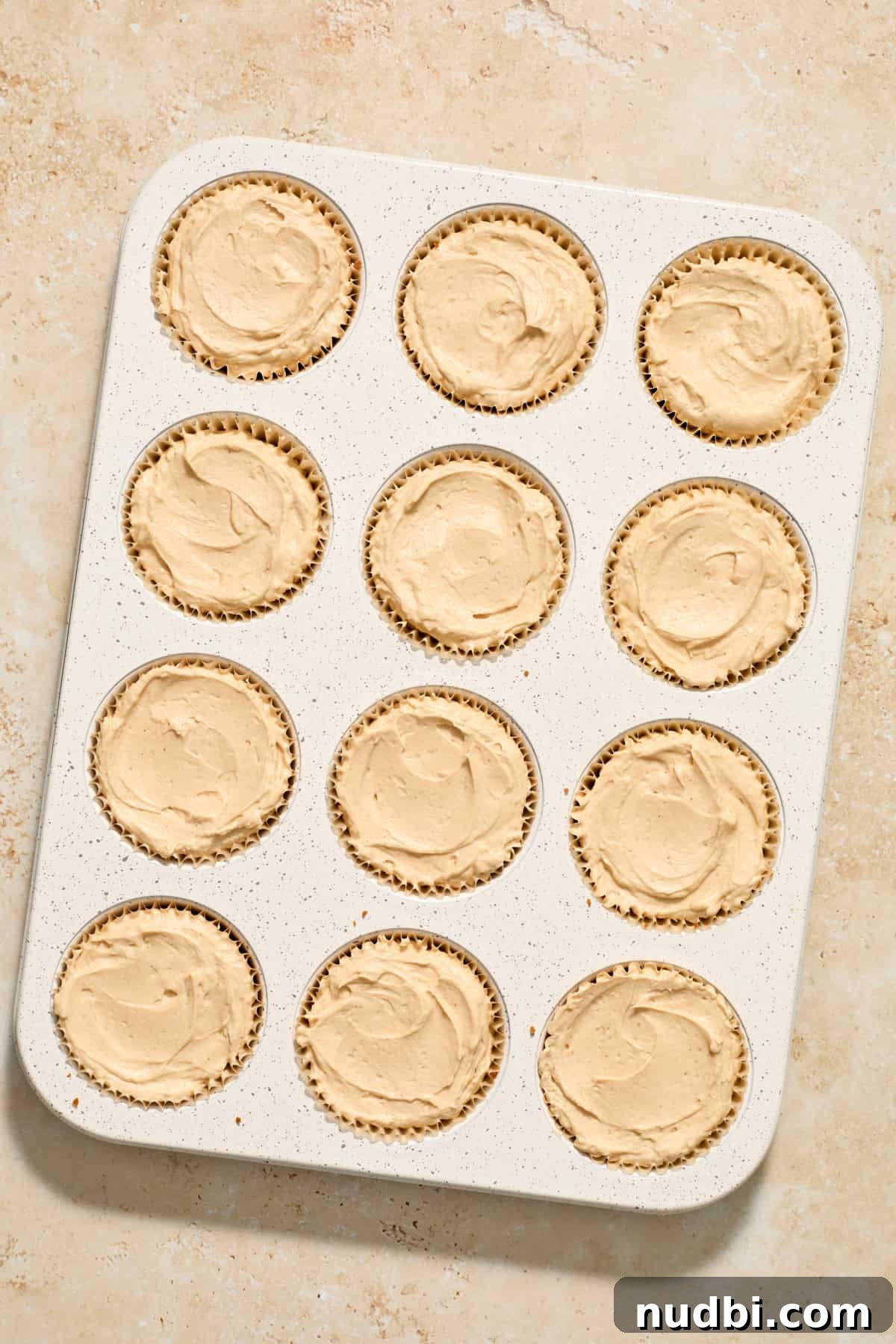 No-Bake Mini Biscoff Cheesecakes Recipe for Crowd-Pleasing Treats 13 Cookie butter mini cheesecakes in muffin tin before chilling.