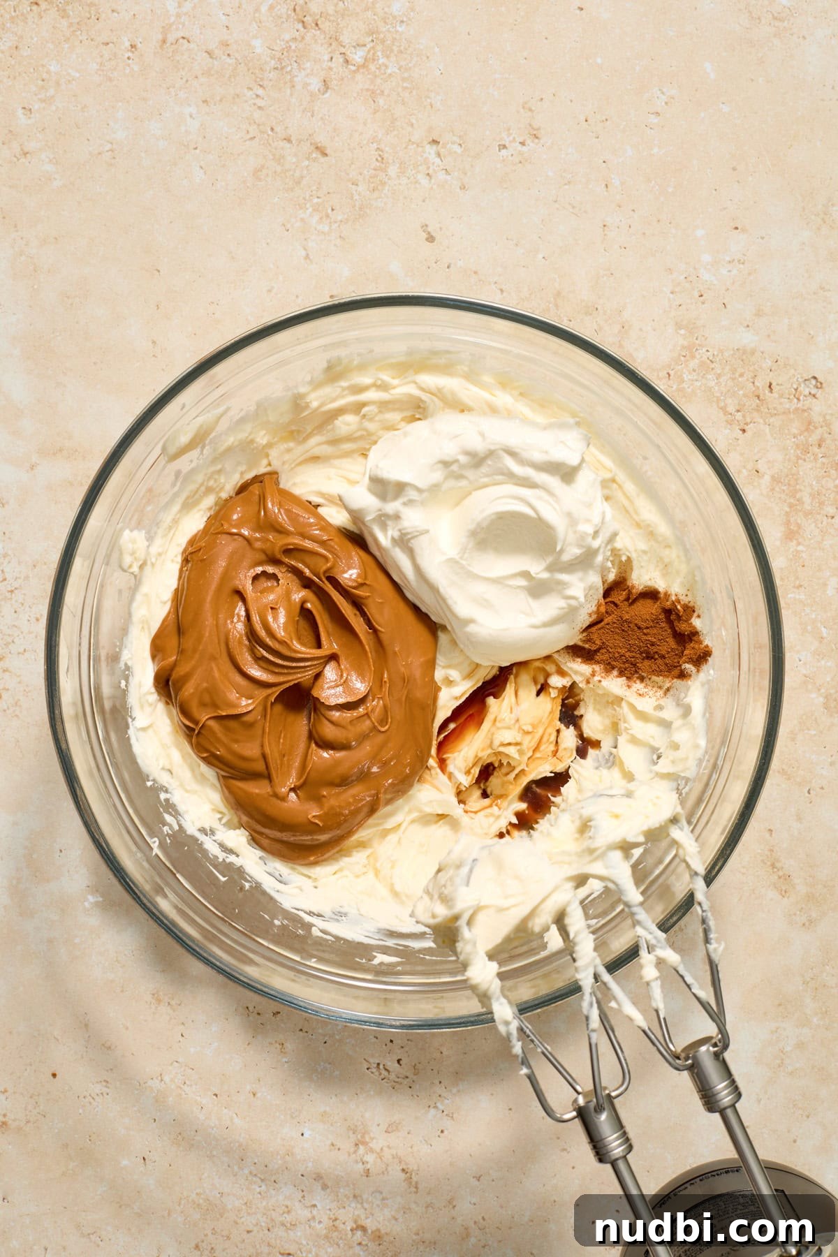 No-Bake Mini Biscoff Cheesecakes Recipe for Crowd-Pleasing Treats 8 Cookie butter, sour cream, and vanilla added to bowl with cream cheese.
