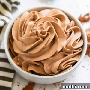 Light and Fluffy Chocolate Whipped Cream Recipe 9 Chocolate whipped cream piped into white bowl with black and white linen beside it.