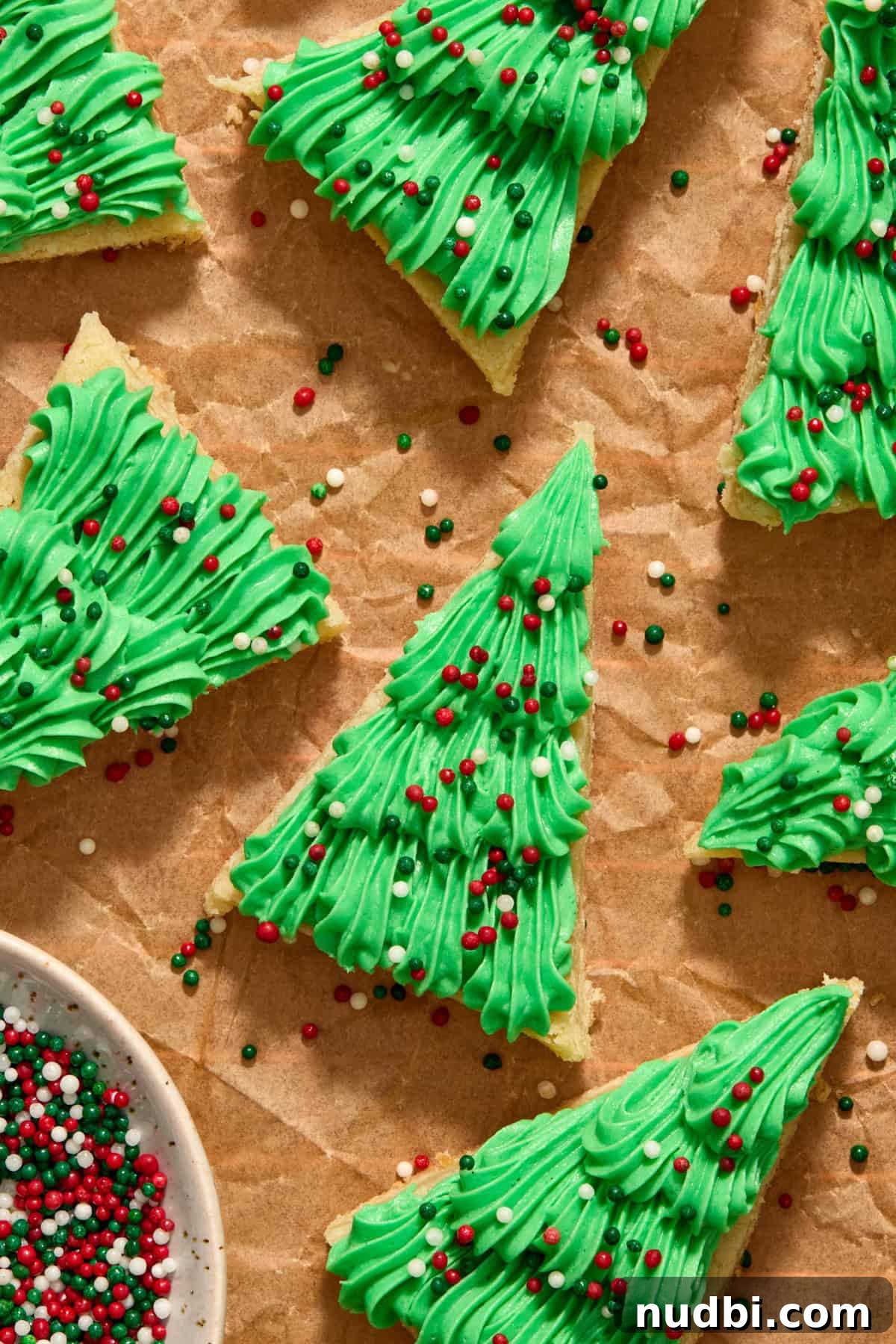 Christmas Sugar Cookie Bars Recipe with Festive Frosting 2 Christmas sugar cookie bars iced with green frosting piped on with sprinkles.