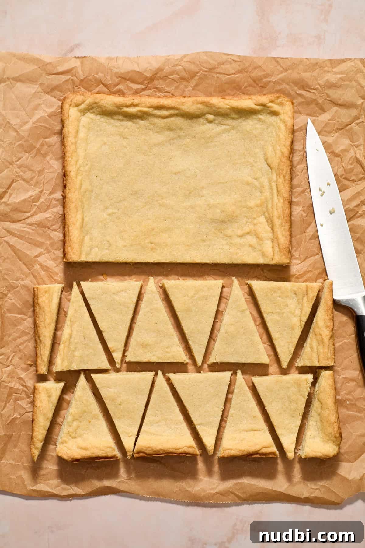 Christmas Sugar Cookie Bars Recipe with Festive Frosting 13 Sugar cookie bars on parchment sliced into triangles.