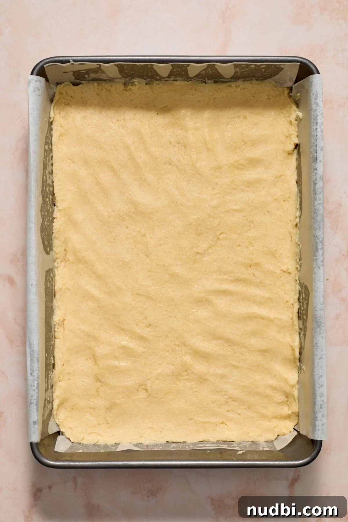 Christmas Sugar Cookie Bars Recipe with Festive Frosting 9 Baking pan with parchment and cookie bar dough pressed in.