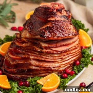 Apricot-Glazed Ham Recipe for Holidays and Entertaining 12 Apricot glazed ham on serving platter with orange slices and cranberries.