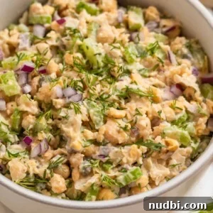 Vegan Chickpea Tuna Salad Recipe — Creamy Plant-Based Lunch 10 Bowl with mashed chickpea mock tuna salad topped with chopped red onion and dill.