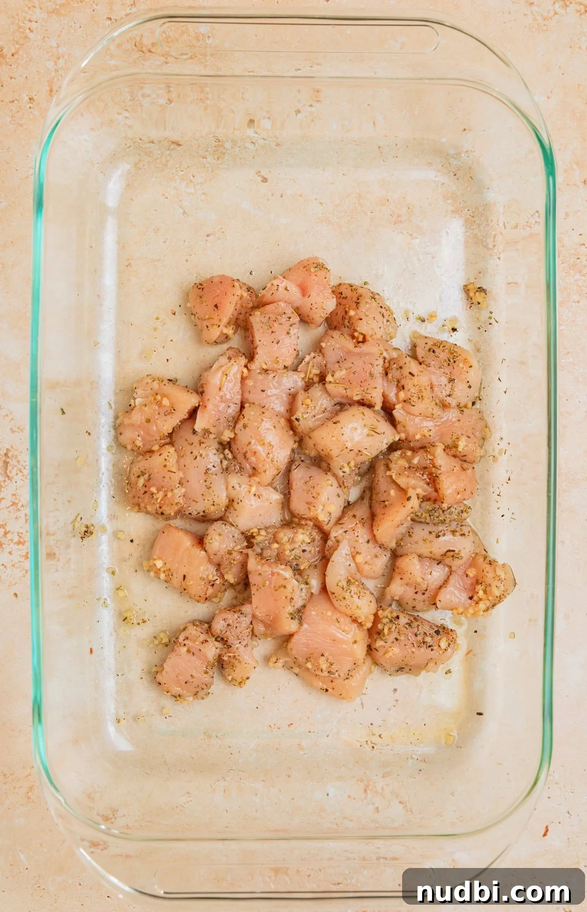 Creamy Baked Chicken and Orzo Casserole for Weeknight Dinners 5 Cubed chicken breast in pan tossed with olive oil and seasoning.
