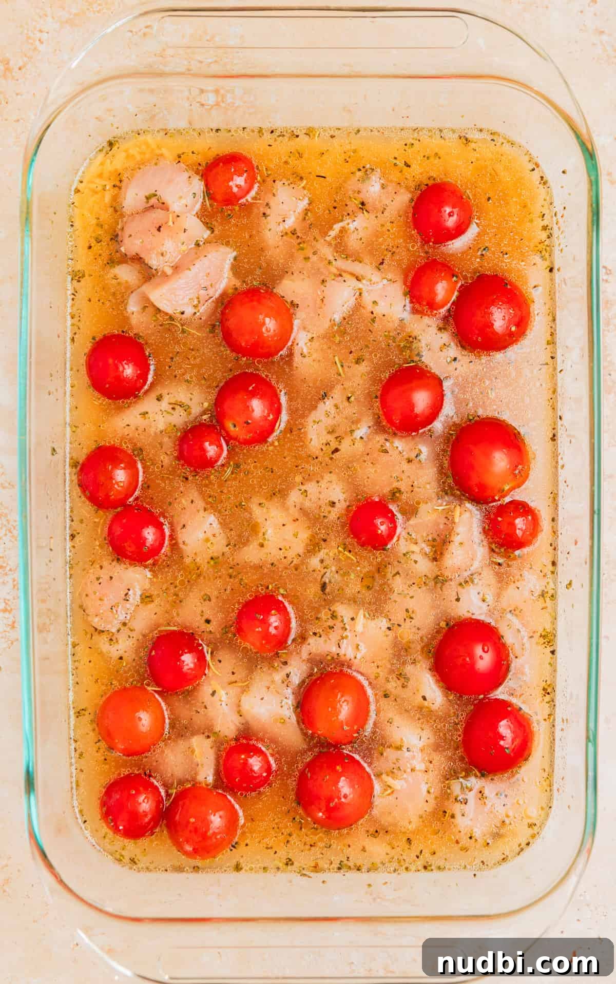 Creamy Baked Chicken and Orzo Casserole for Weeknight Dinners 6 Broth, orzo and tomatoes added to baking pan with chicken.