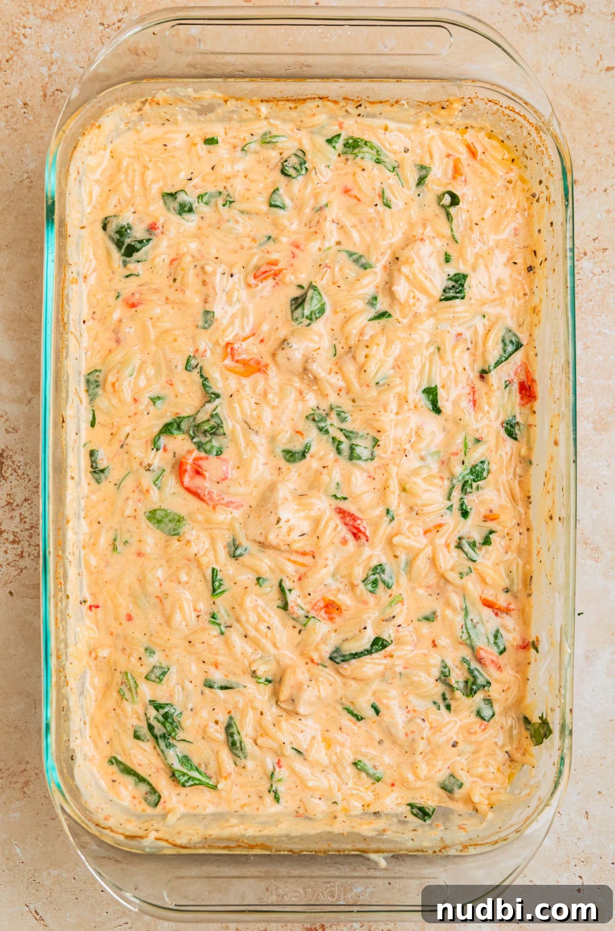 Creamy Baked Chicken and Orzo Casserole for Weeknight Dinners 10 Baking dish with creamy baked chicken orzo with spinach and basil added.