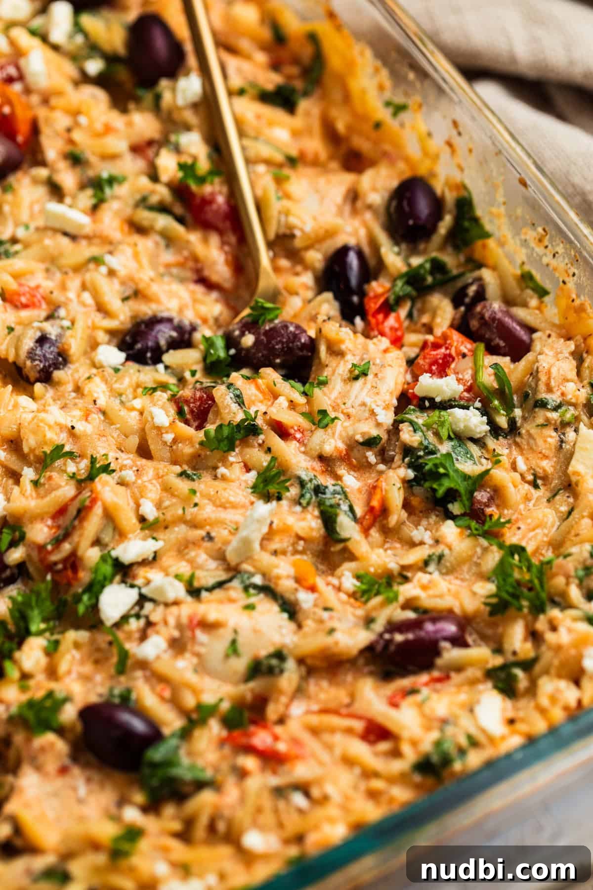 Greek Chicken with Lemon Orzo Pilaf: Flavorful Mediterranean Recipe 2 Greek chicken and orzo in glass pan with spoon scooping into it.