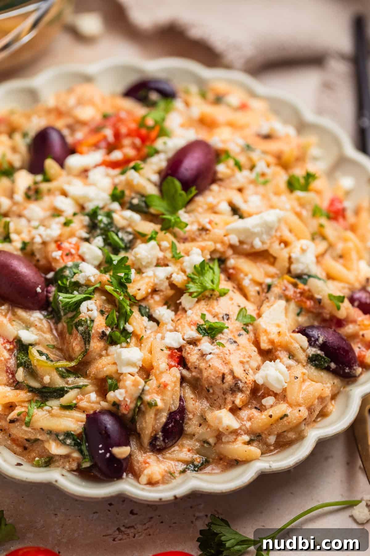 Greek Chicken with Lemon Orzo Pilaf: Flavorful Mediterranean Recipe 11 Plate with chicken and orzo with feta cheese, kalamata olives and chopped parsley on top.