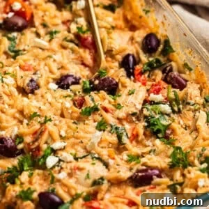 Greek Chicken with Lemon Orzo Pilaf: Flavorful Mediterranean Recipe 16 Creamy feta baked chicken and orzo topped with olives, parsley and basil in pan.