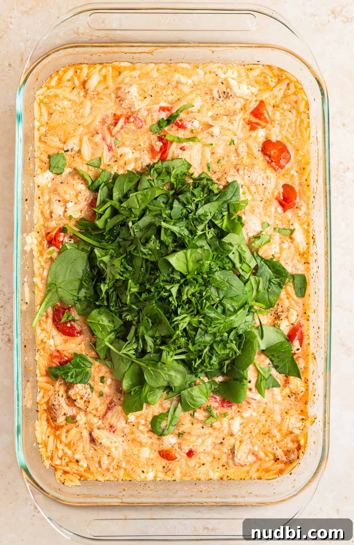 Greek Chicken with Lemon Orzo Pilaf: Flavorful Mediterranean Recipe 9 Chopped spinach and parsley on top of pan with chicken orzo bake.