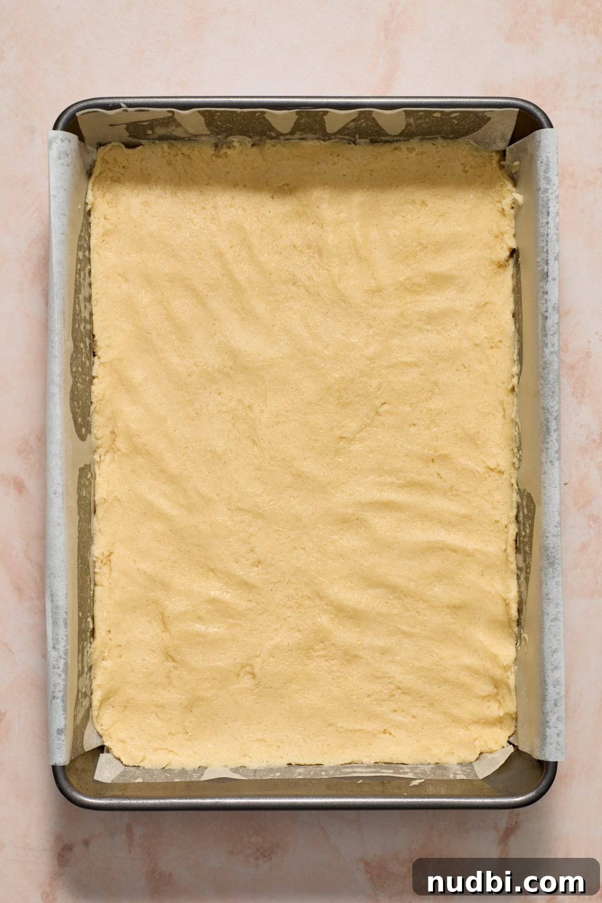 Frosted Sugar Cookie Bars Recipe — Soft, Chewy Dessert Bars 9 Sugar cookie dough pressed into parchment lined baking sheet.