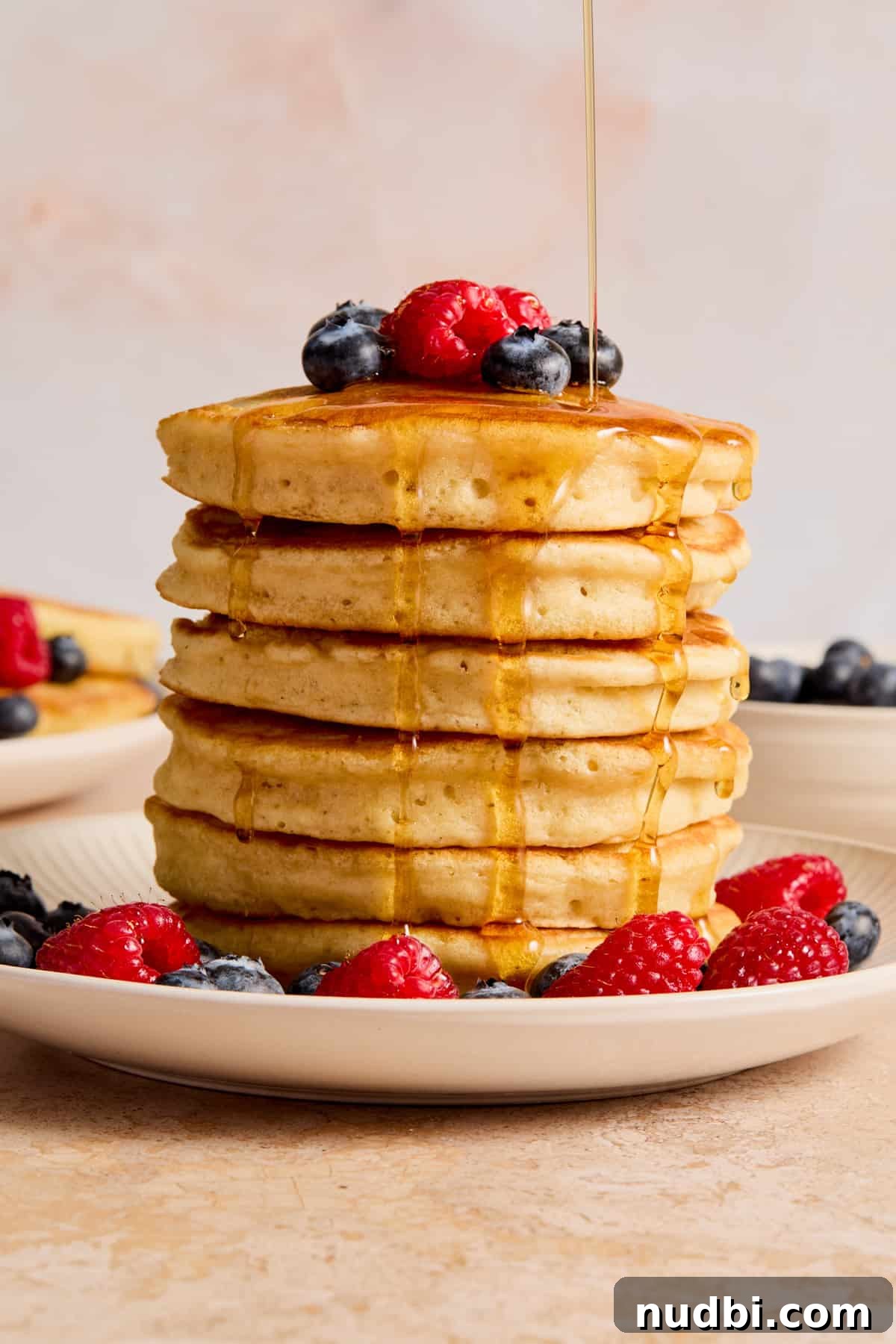 Fluffy Dairy-Free Pancakes: Simple Vegan Breakfast Recipe 2 Stack of dairy free pancakes on plate with berries and maple syrup drizzling over top.