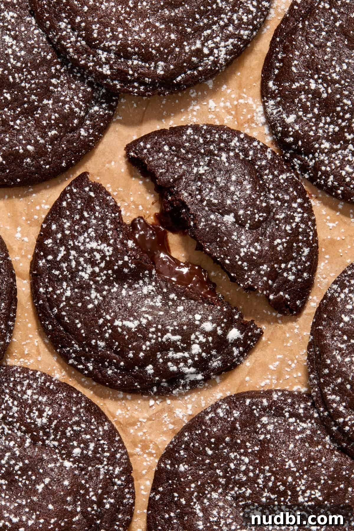 Molten Chocolate Lava Cookies Recipe: Gooey Center Cookies Tutorial 2 Chocolate lava cookies on parchment with one cookie split in half to show chocolate center.