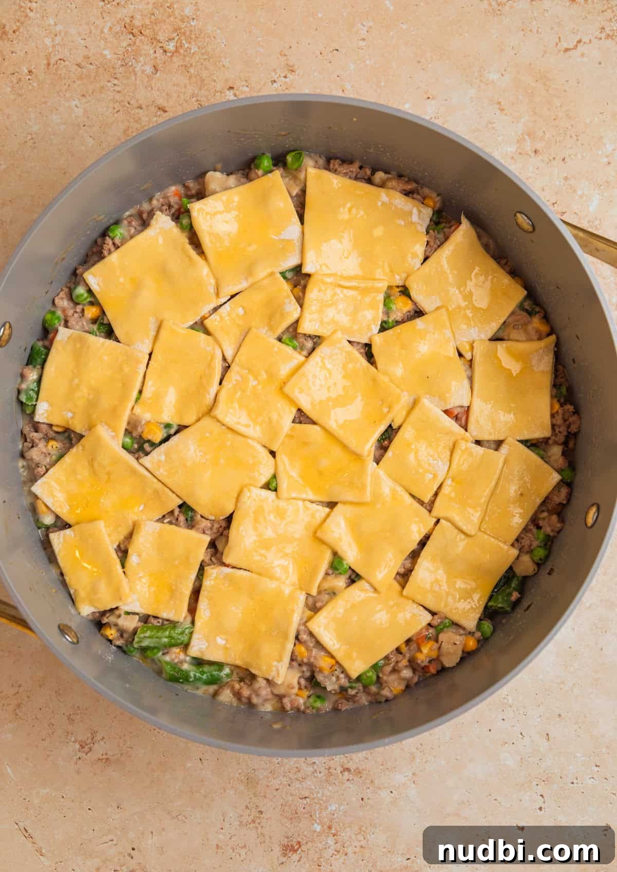 Savory Ground Turkey Pot Pie Recipe for Comforting Dinners 7 Pieces of puff pastry layered over top of meat and vegetable mixture before baking.