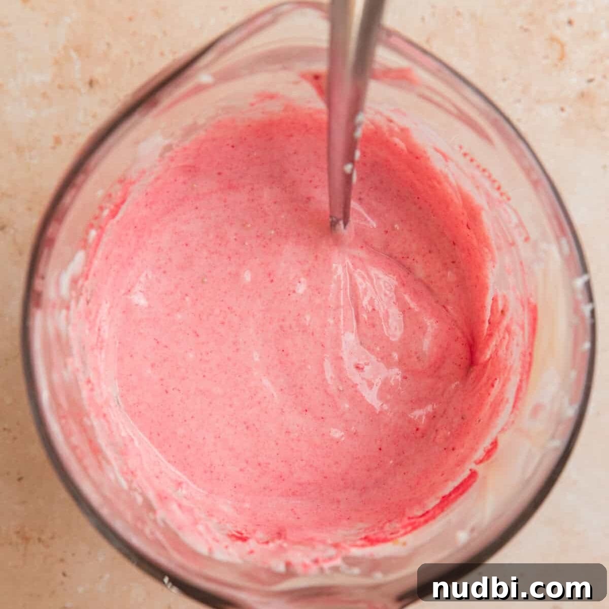 Strawberry Chex Mix Recipe: Sweet, Crunchy Snack for Parties 7 Pink melted white chocolate mixture in glass with spoon.