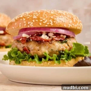 Turkey burger with spinach and feta on bun with lettuce, onion and other ingredients.