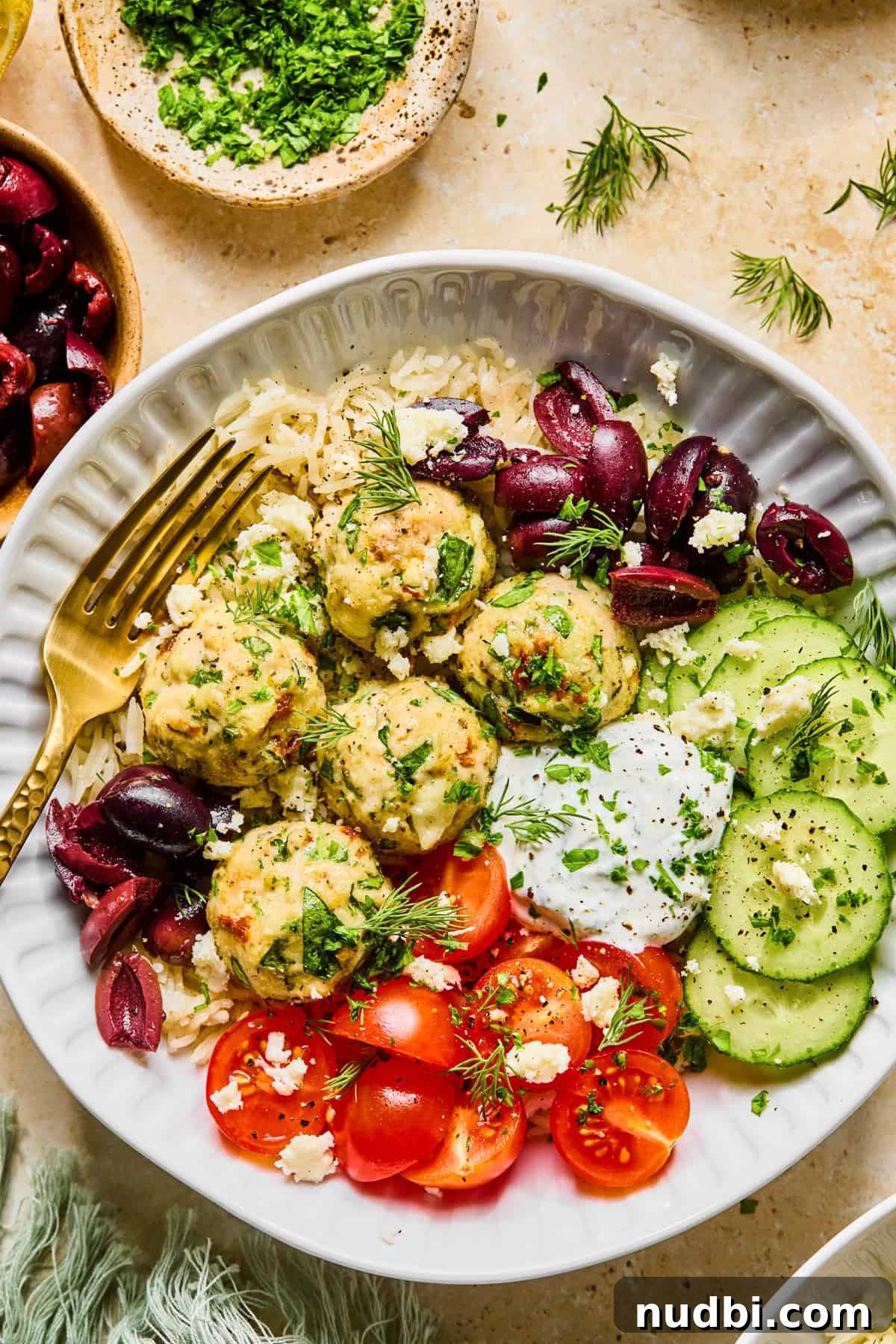 Spinach and Feta Turkey Meatballs with Garlic Herb Sauce 2 Spinach and feta turkey meatballs in bowl with yogurt sauce, cucumbers, olives and more.