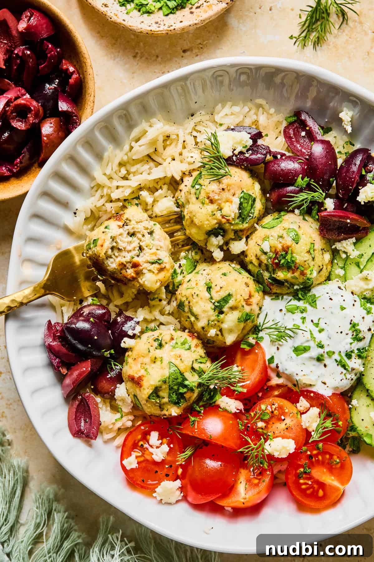 Spinach and Feta Turkey Meatballs with Garlic Herb Sauce 11 Fork in turkey feta meatball in rice bowl with dill yogurt sauce.
