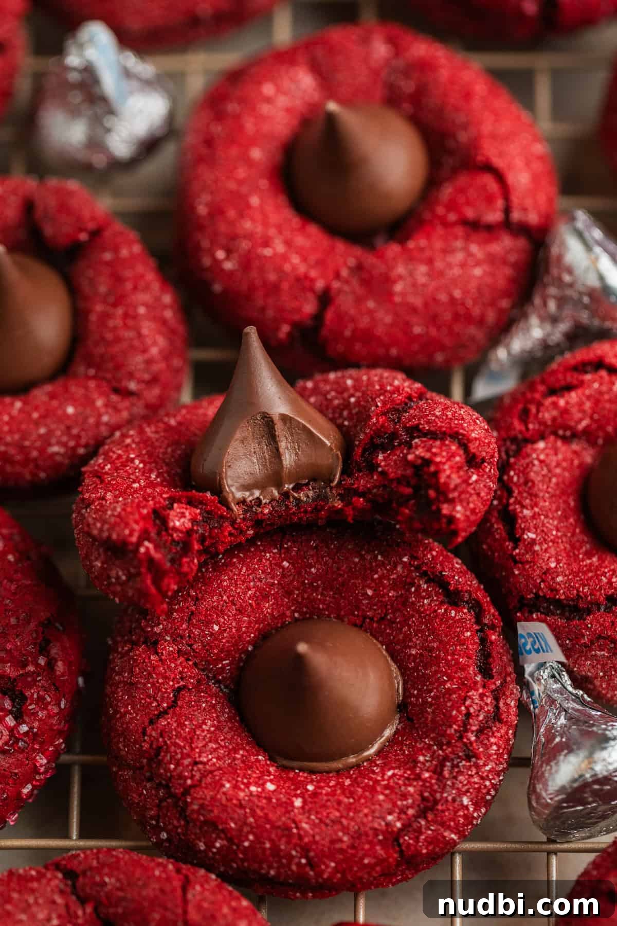 Red Velvet Blossom Cookies Recipe — Soft, Cream Cheese Frosting 11 Bite taken out of red velvet cake mix blossom cookie on cooling rack with other cookies.