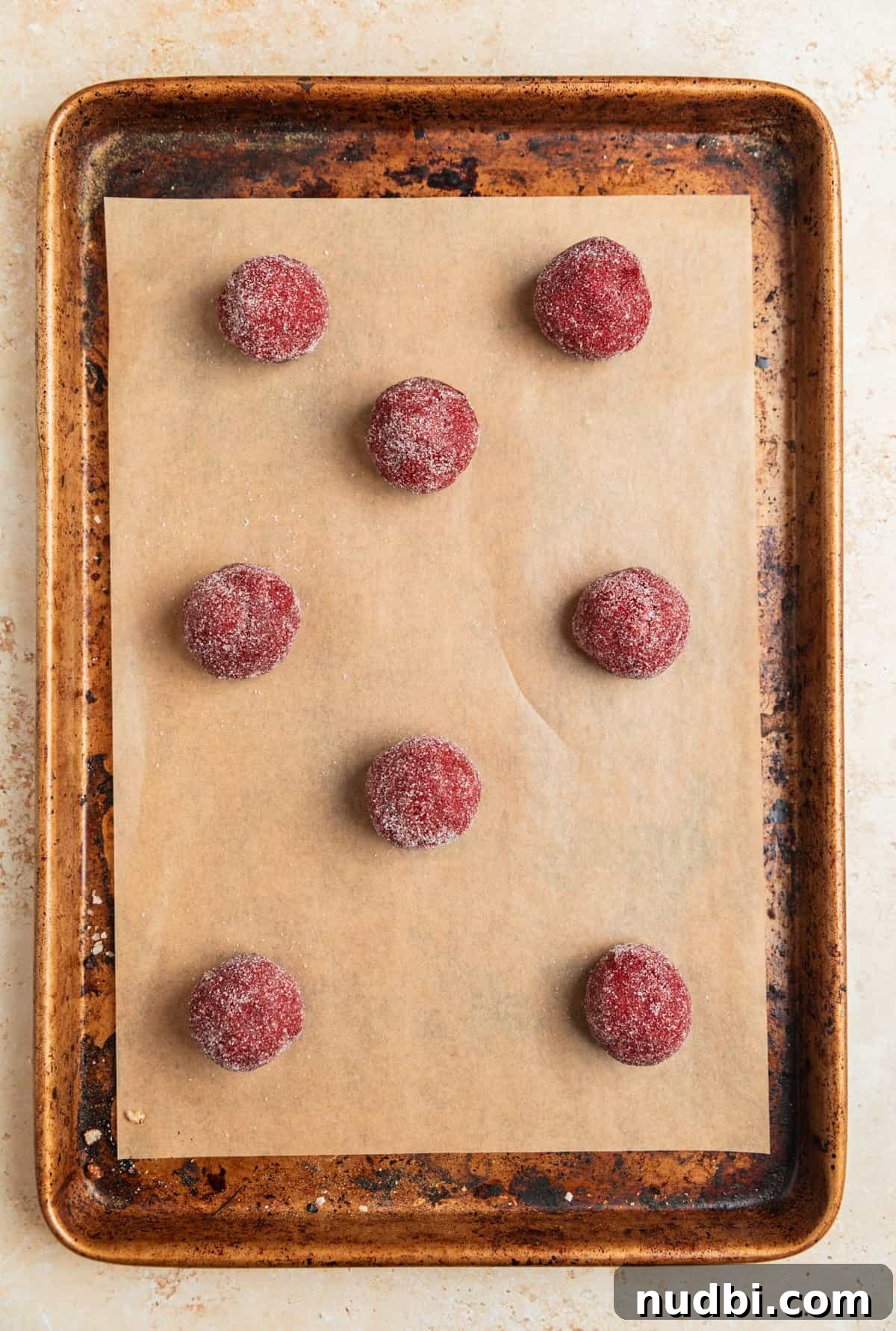 Red Velvet Blossom Cookies Recipe — Soft, Cream Cheese Frosting 9 Red velvet cake mix cookie dough balls rolled in sugar on cookie sheet.