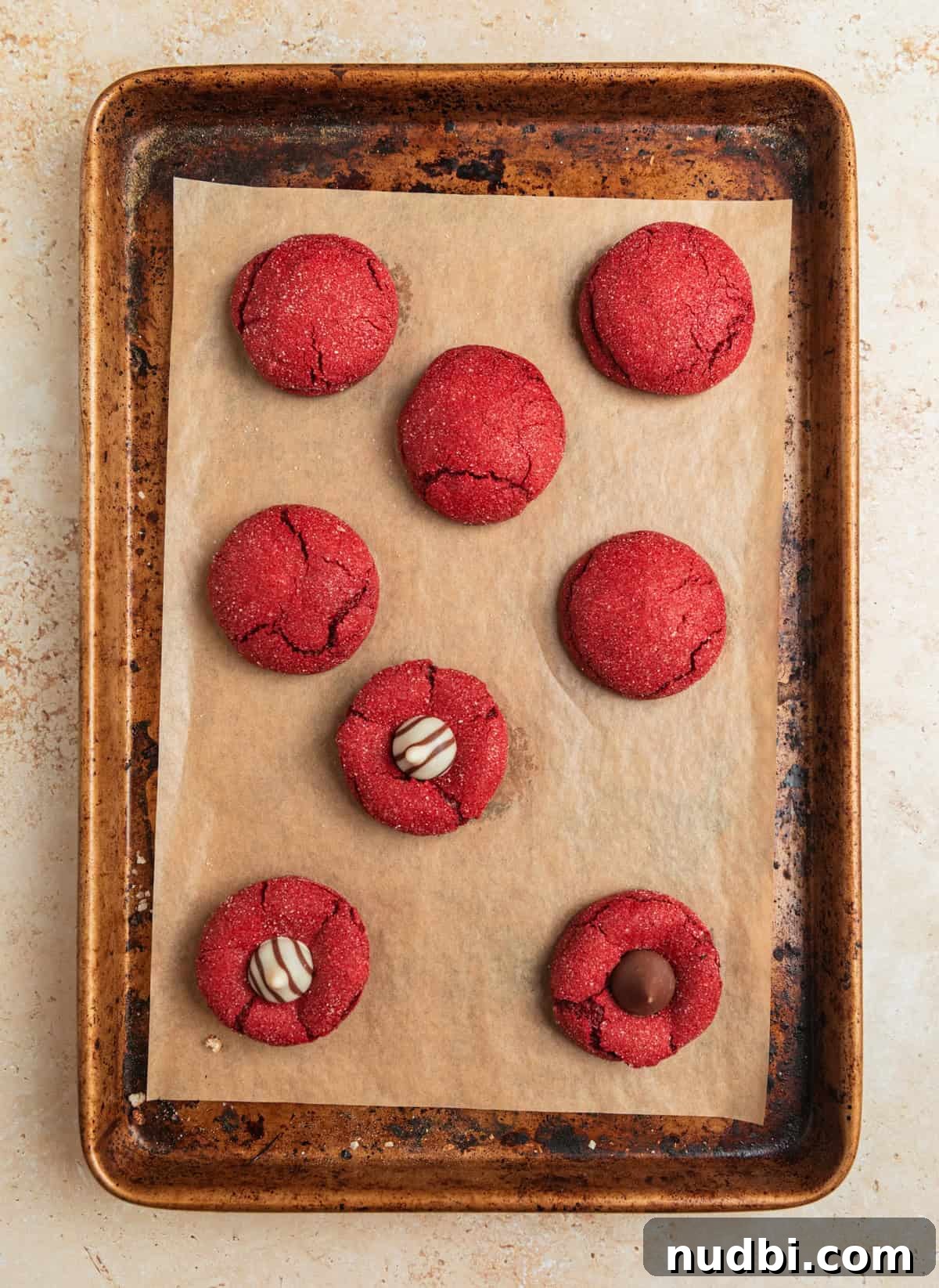 Red Velvet Blossom Cookies Recipe — Soft, Cream Cheese Frosting 10 Baked red velvet cookies on pan with Hershey Kiss and Hugs pressed into some of the cookies.
