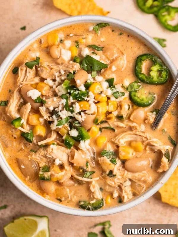 Slow-Cooker Sausage and Tortellini Soup Recipe 16 White bowl with white chicken chili with toppings and spoon.
