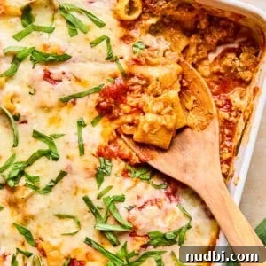 Pasta bake with Italian sausage in pan with spoon scooping in.