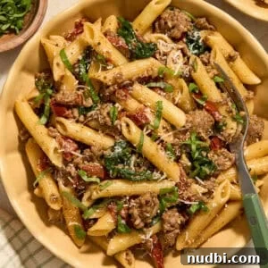 Plate with sun-dried tomato pasta topped with parmesan and chopped basil.